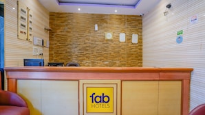 A reception desk with a wooden finish, a clock, and a sign for 'fab hotels'. - Fabexpress New Deepak (Mumbai)