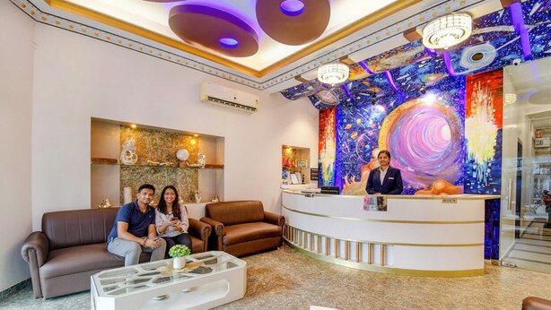 A hotel lobby with a reception desk, seating area, and a colorful mural on the wall. - Fabhotel Prime Rockstar Suites (Kolkata)