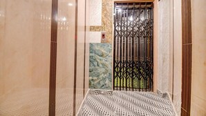 An elevator with a patterned floor, a marble wall, and a metal gate. - Fabhotel Prime Rockstar Suites (Kolkata)