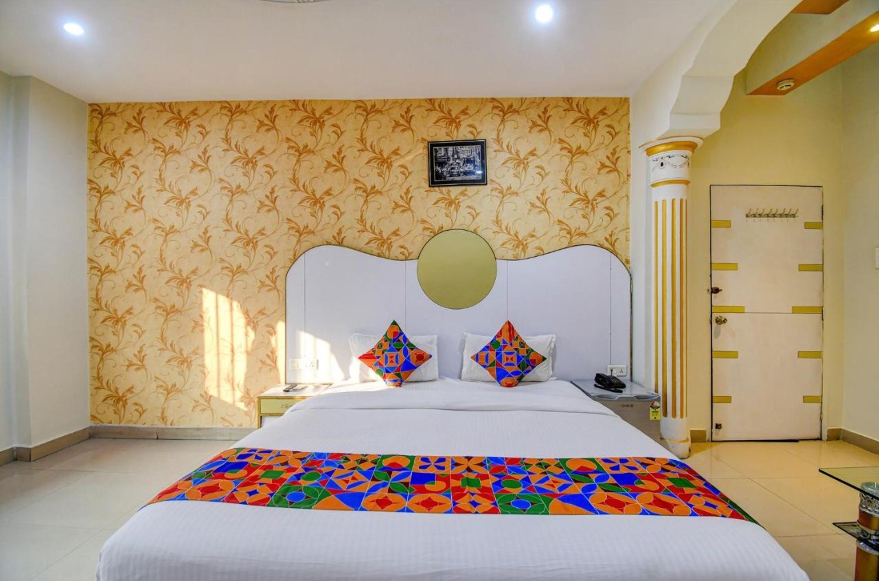 A hotel room with a large bed, a nightstand, a wall-mounted telephone, and a door with a lock.