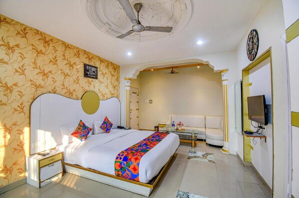 A hotel room with a large bed, a TV, a desk, and a sofa. - Fabhotel Prime Rockstar Suites (Kolkata)