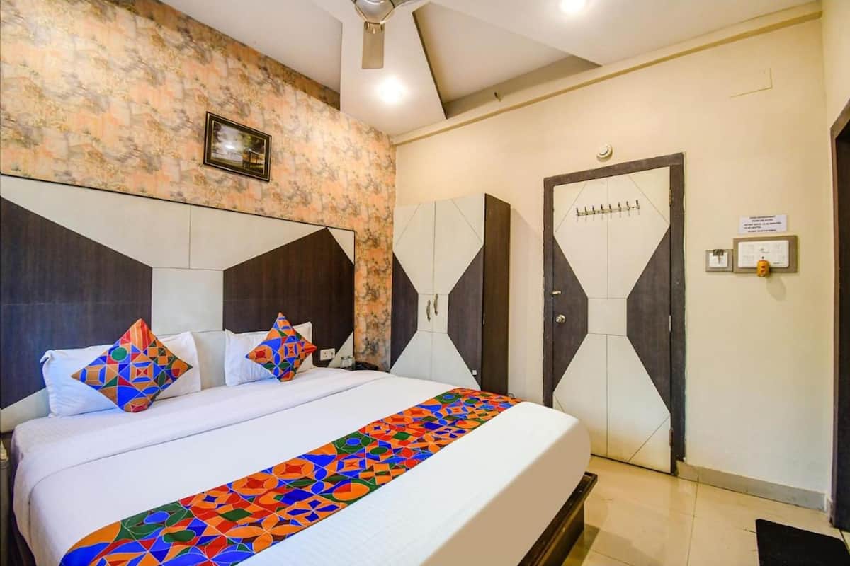 Una habitación de hotel con una cama grande, un edredón de estampado geométrico, un muro con diseño de mármol y una puerta con cerradura de seguridad.