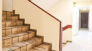 A staircase with a wooden handrail and beige walls. - Fabexpress Gargi Executive (Pune)