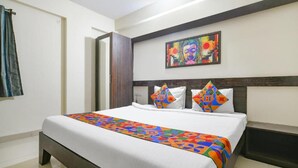 Una camera d'hotel con un letto grande, una coperta colorata e un quadro appeso al muro.