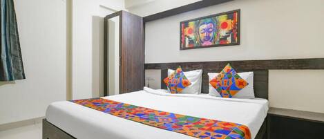 Una habitación de hotel con una cama grande, un edredón colorido y un cuadro en la pared.