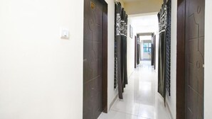 Un corridoio con porte in legno scuro, pavimento chiaro e un interruttore della luce a parete.