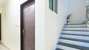 Un corridoio con una porta marrone e una scala con gradini neri.