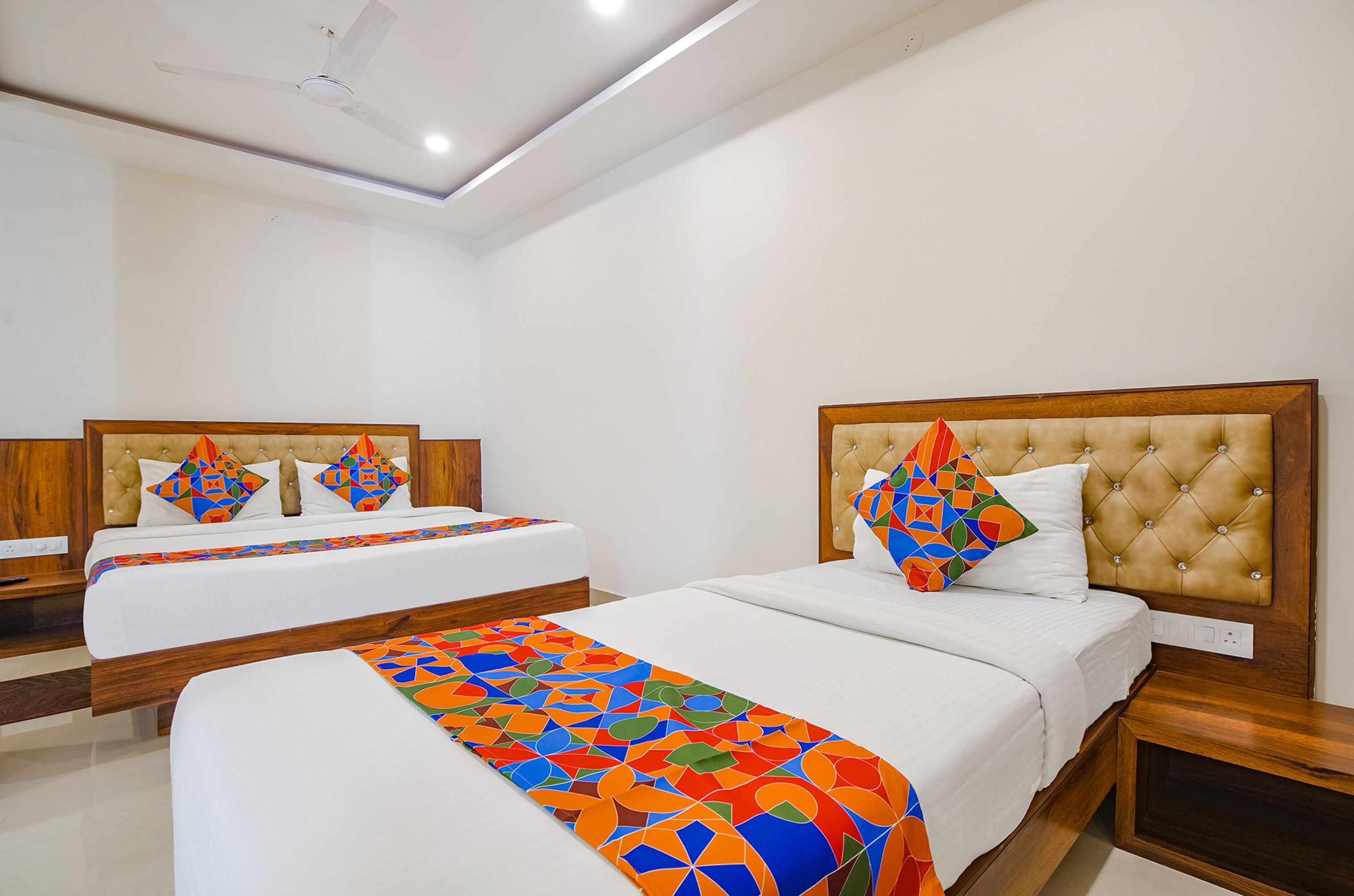 A hotel room with two beds, a ceiling fan, and a large window.