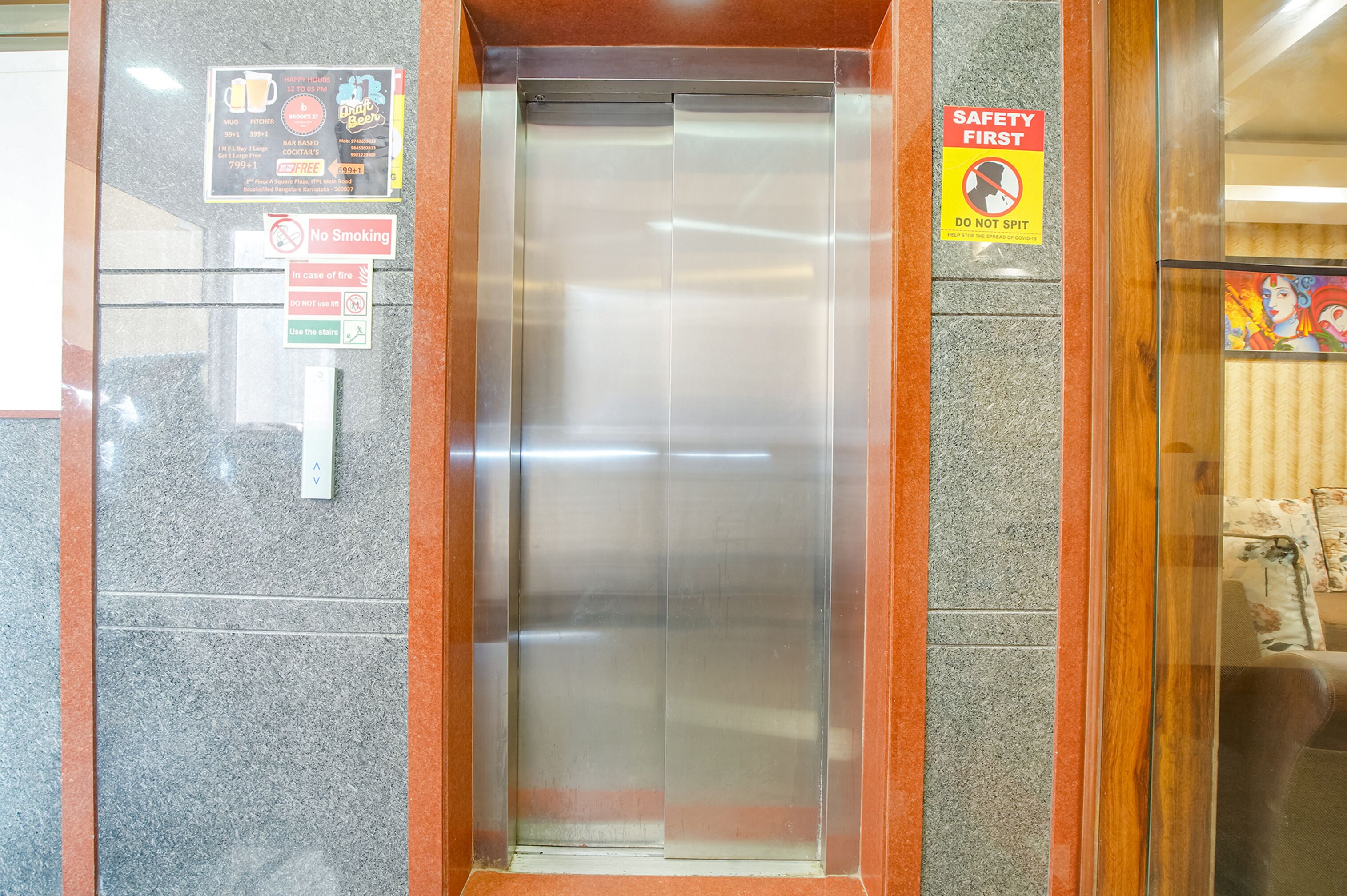 An elevator with safety and no smoking signs, and a menu board advertising coffee and cocktails.