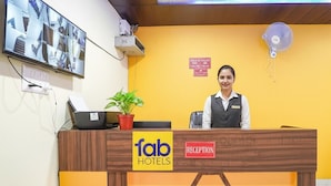 A reception desk with a 'fab hotels' sign, a reception area, and a wall-mounted television.