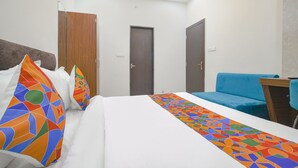 A hotel room with a bed, a blue sofa, and two doors.