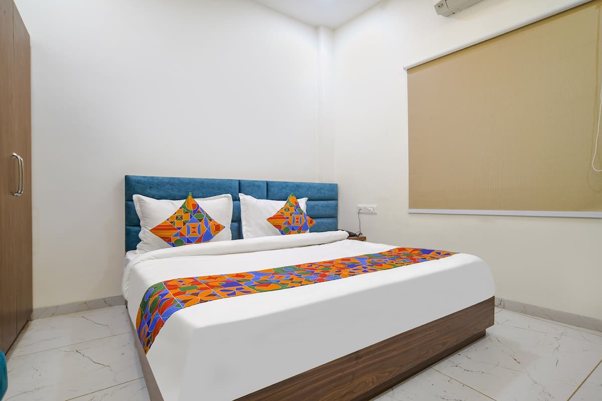 A neatly made bed with a blue headboard, white bedding, and colorful pillows.