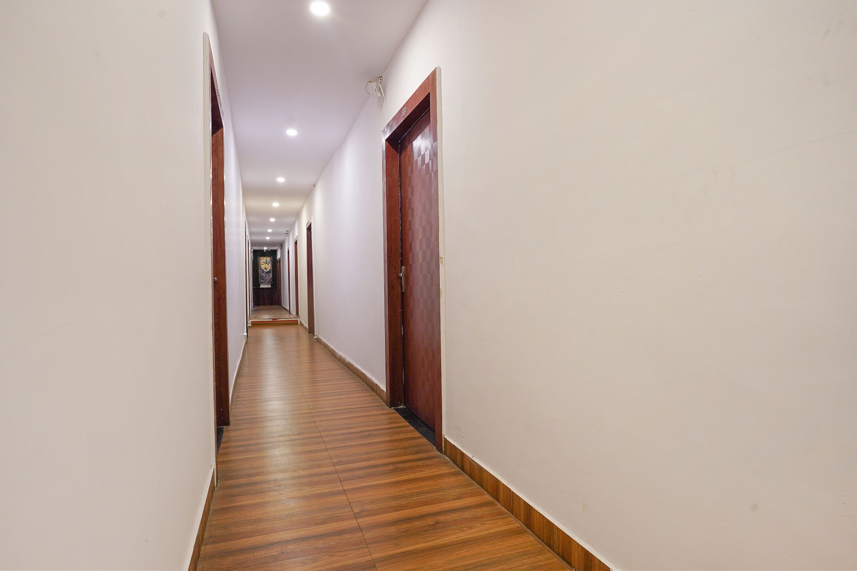 A long, narrow hallway with wooden flooring and white walls.
