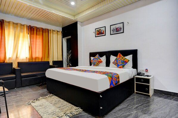 A modern bedroom with a black bed, colorful pillows, a small bedside table, and a nightstand. - Fabexpress Gauri Shree (Bhopal)