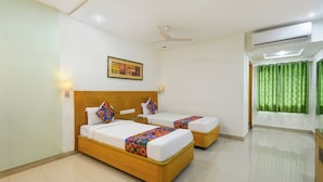 A hotel room with two beds, a ceiling fan, an air conditioning unit, and a green curtain. - FabHotel A&M - Nr. LV Prasad Institute, Banjara Hills (Hyderabad)