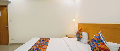 A hotel room with a large bed, a wooden headboard, and a nightstand.