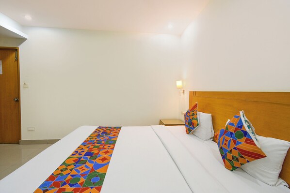 A hotel room with a large bed, a wooden headboard, and a nightstand.