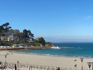 A beach with a stone wall, a boat, and buildings in the background. - Apartment with WIFI and Sea View, Trestraou Beach in Perros-Guirec (Perros-Guirec)