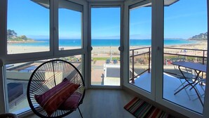 Una habitación con vista a la playa, una silla y una mesita.
