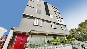 A multi-story building with a flat facade, large windows, and a red door. - Fabhotel Lupin International (Udaipur)