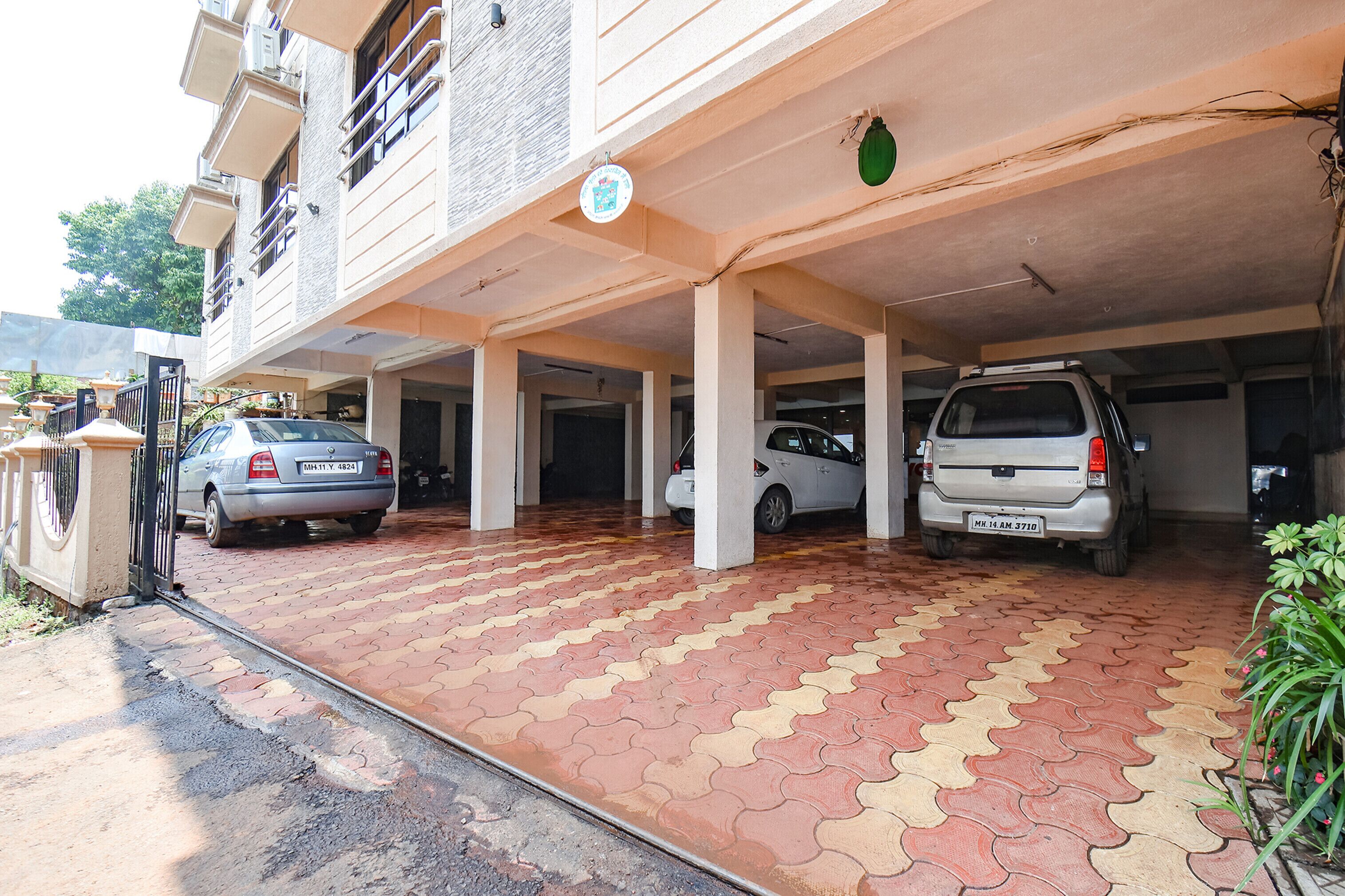 A covered parking area with two cars parked, a tiled floor, and a building entrance.