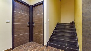 A hallway with two doors labeled 201 and 202, a staircase with black steps, and a yellow wall. - Fabhotel Resolute (Jaipur)