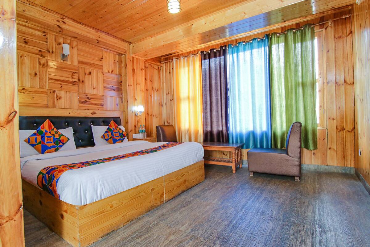 A wooden cabin-style room with a large bed, a chair, and a small table.