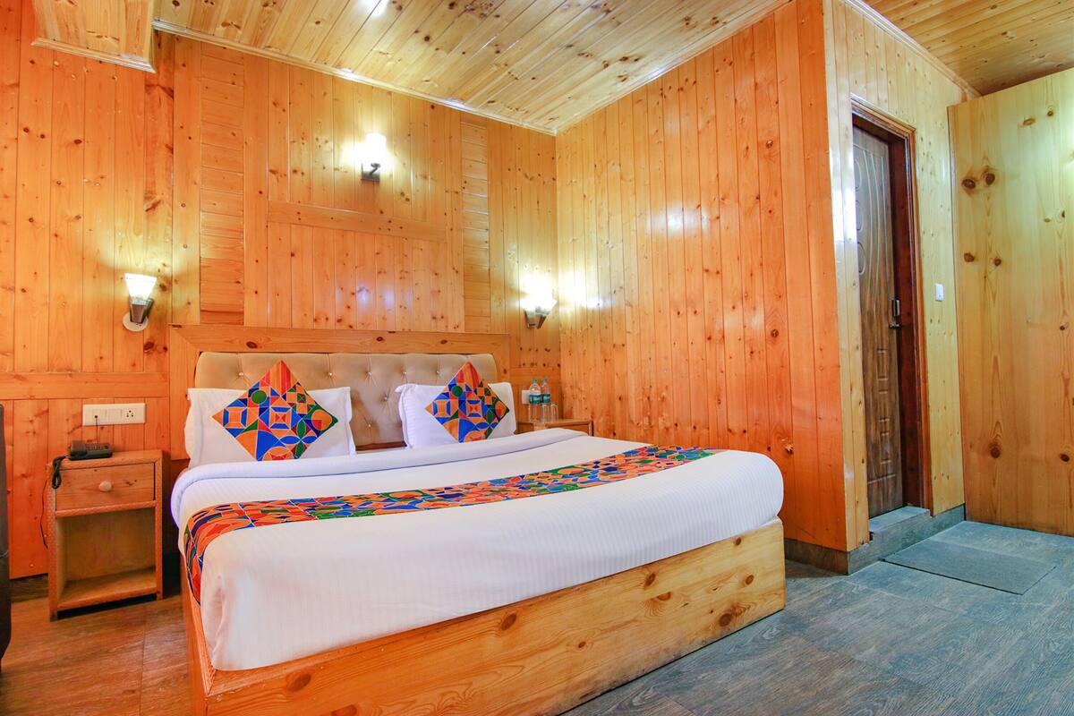 A wooden-paneled bedroom with a bed, nightstand, and wall-mounted lights.