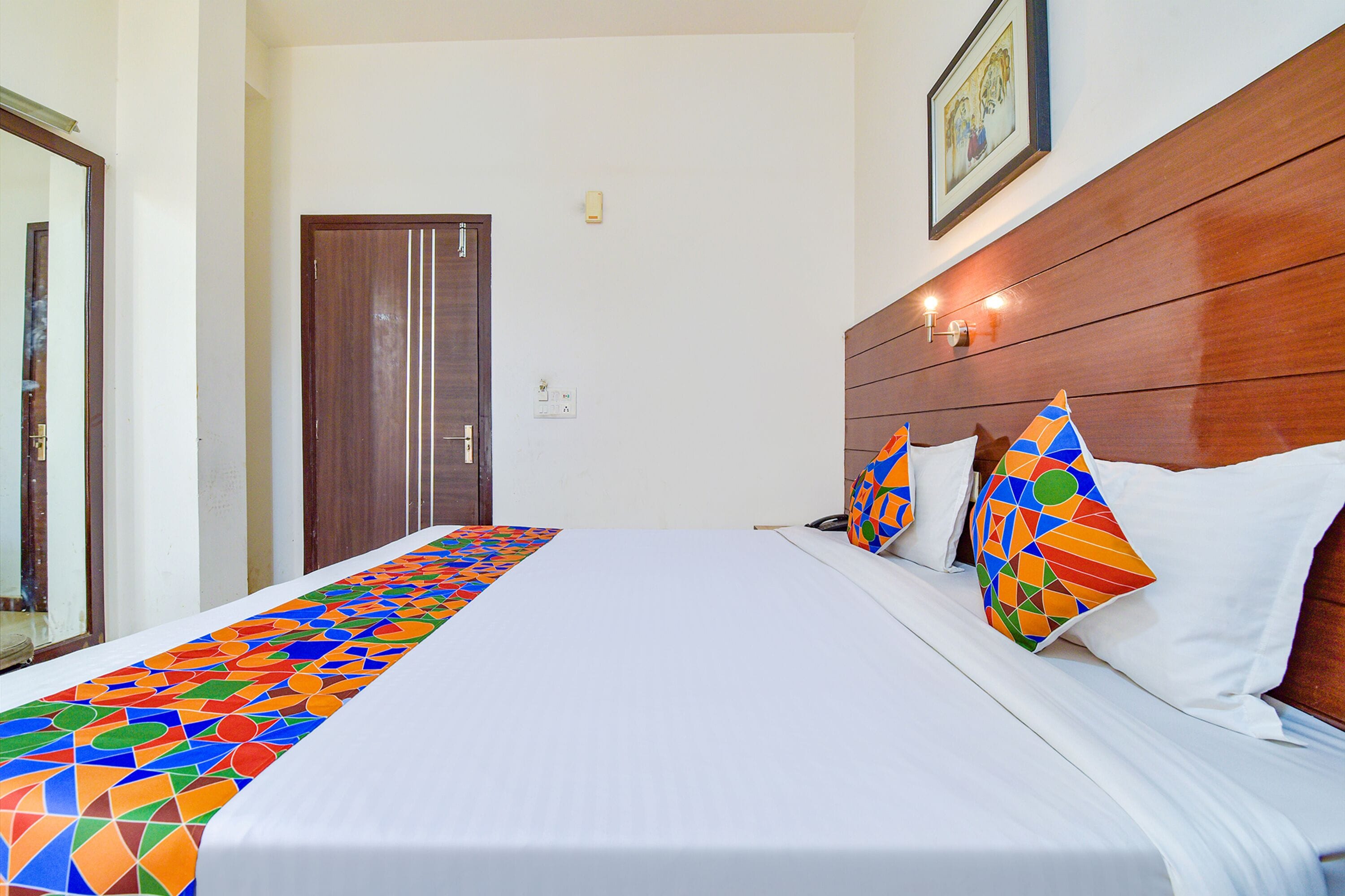 Una camera d'albergo con un letto grande, una testiera in legno e un corridore per il letto con un motivo geometrico colorato.