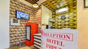 Un espace d’accueil comprenant un comptoir de réception, un téléviseur fixé au mur et une horloge.