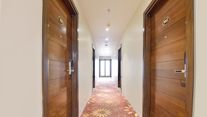 Un couloir avec des portes en bois, une moquette à motifs et un luminaire au plafond.