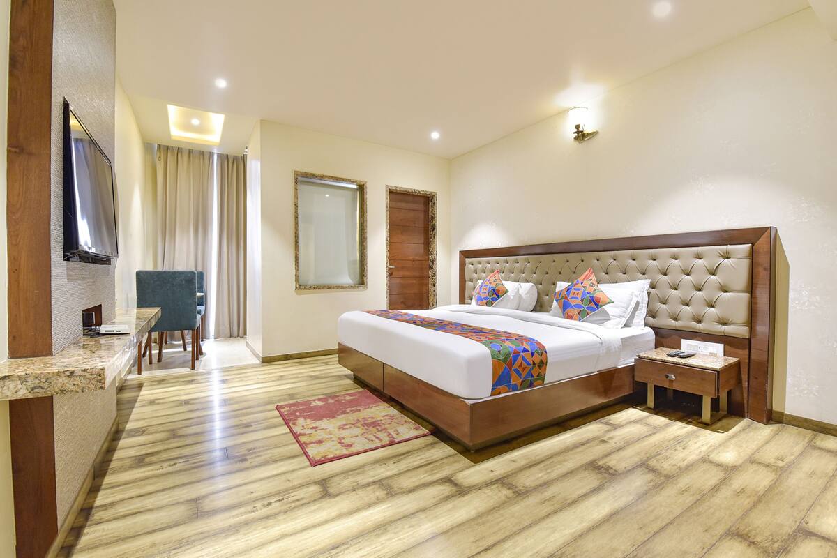 Una habitación de hotel con una cama grande, un escritorio, una silla, un televisor y la puerta del baño.