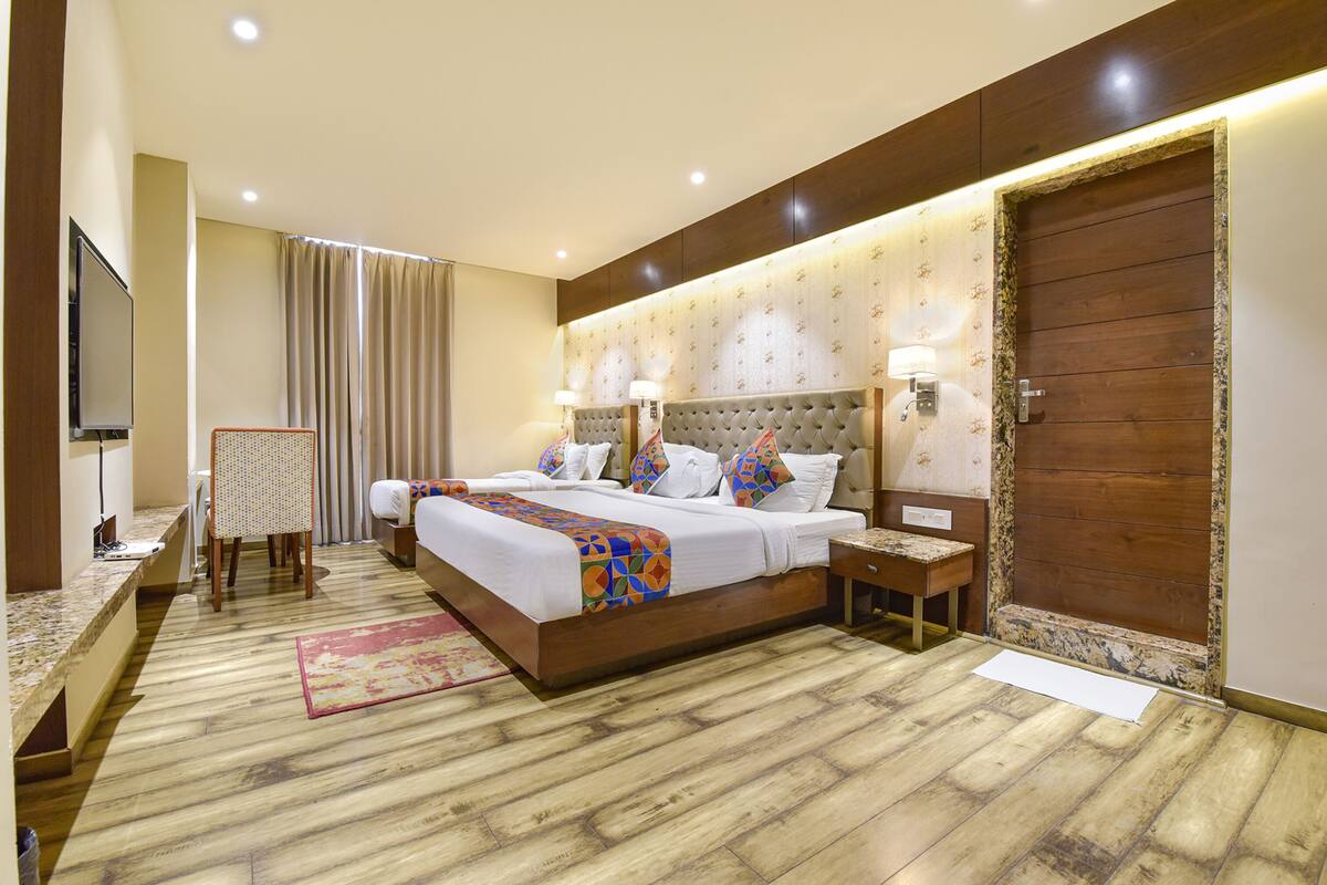 Habitación de hotel con una cama grande, dos mesitas de noche, un televisor y suelo de madera.