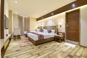 A hotel room with a large bed, two bedside tables, a TV, and a wooden floor. - Fabhotel Prime The Wish (Jaipur)
