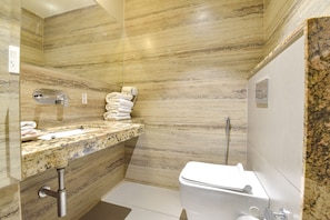 A modern bathroom with a marble countertop, a sink, a toilet, and a shower area. - Fabhotel Prime The Wish (Jaipur)