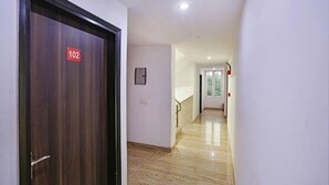 A hallway with a wooden door marked '102', a light switch, and a staircase leading to another room. - FabHotel Taj Home Stay (New Delhi)
