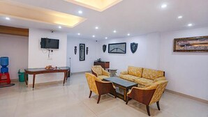 A spacious living room with a sofa set, a coffee table, and a television mounted on the wall. - FabHotel Taj Home Stay (New Delhi)