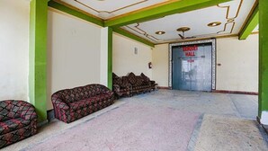 A room with patterned sofas, a green accent wall, and a door labeled "Banquet Hall". - Fabhotel Shivam Palace (Varanasi)