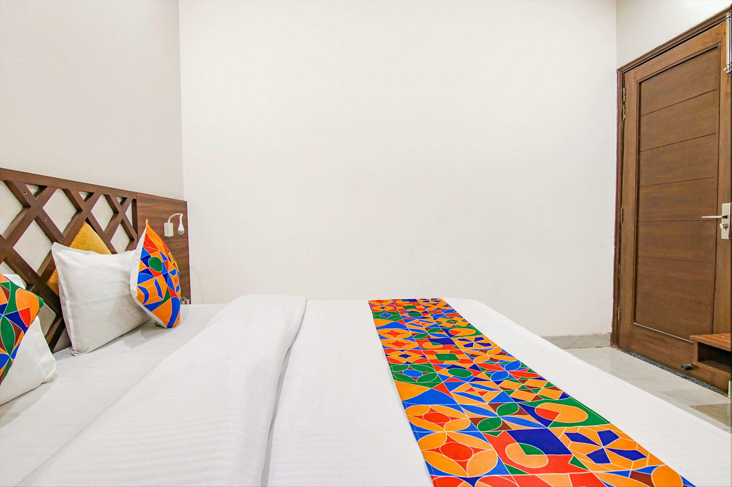 Una habitación de hotel con una cama, cabecera de madera, un corredor colorido y un armario de madera.