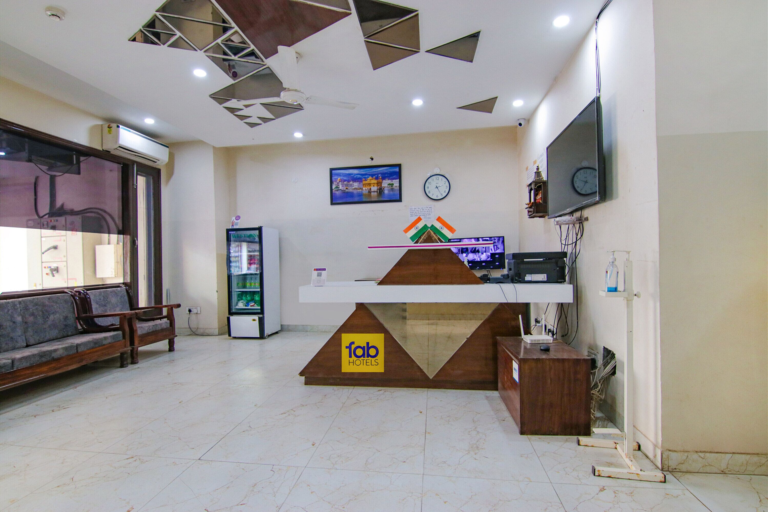 A hotel reception area with a reception desk, a sofa, a clock, and a television.