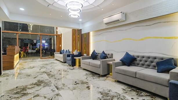 A spacious lobby with a marble floor, a grey sofa set with blue cushions, a round coffee table, and a modern chandelier. - Fabhotel Elite Residency (Indore)