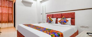 A hotel room with a large bed, a red headboard, and a colorful bedspread. - Fabhotel Elite Residency (Indore)