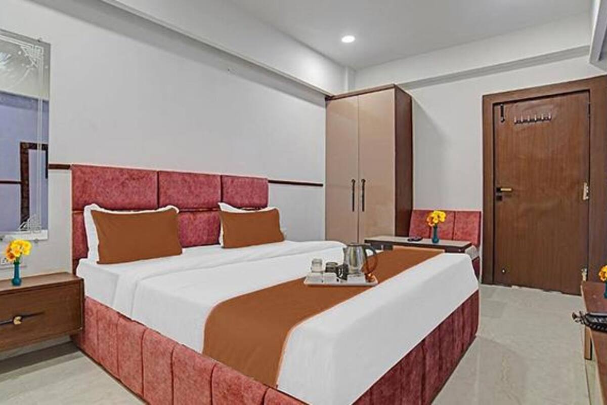 A hotel room with a bed, a nightstand, a wardrobe, and a desk with a chair.