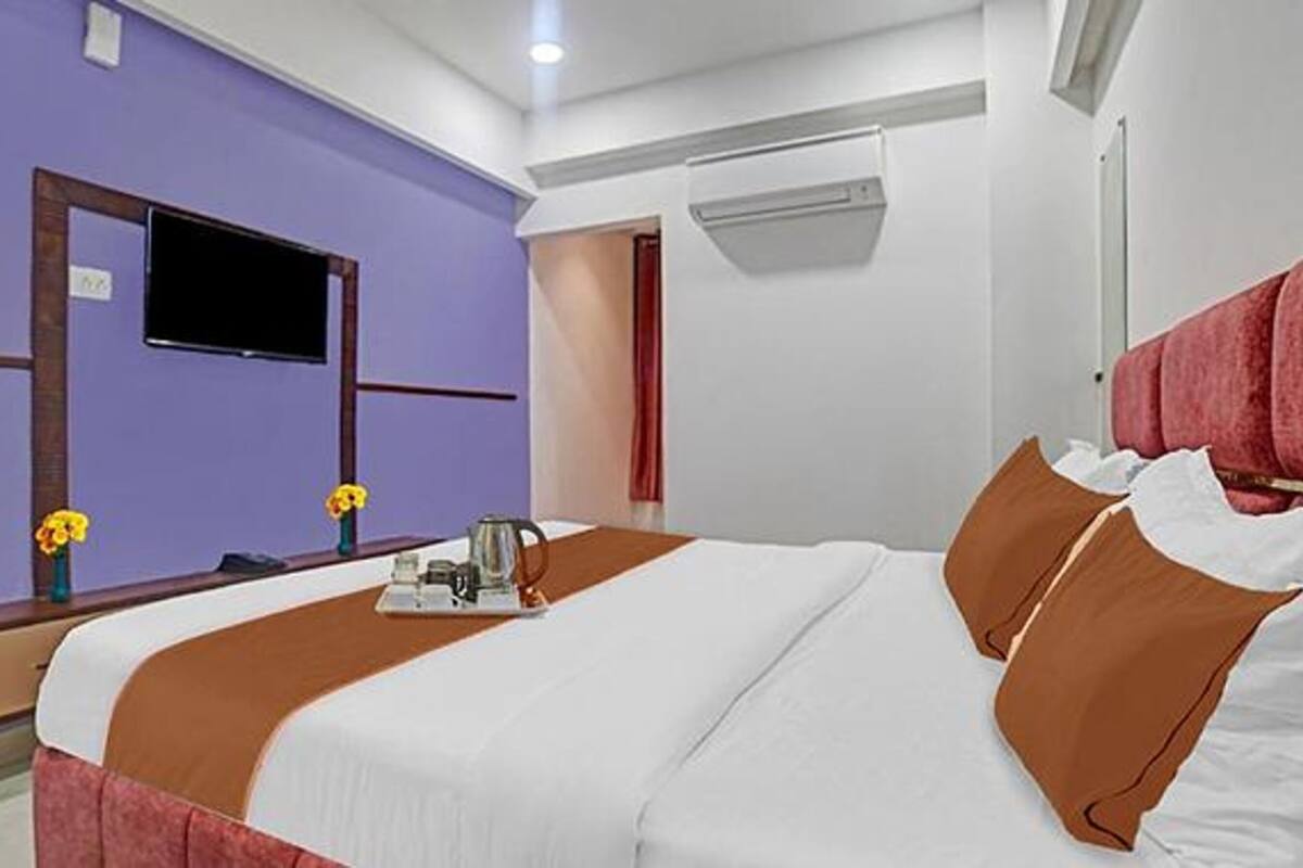 A hotel room with a bed, a TV, a desk, and a window.