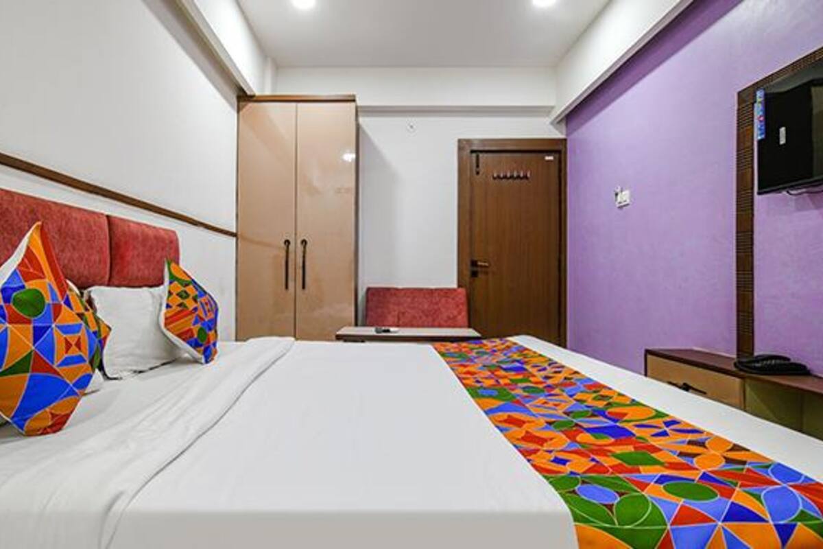 A bedroom with a bed, a wardrobe, a door, and a television.