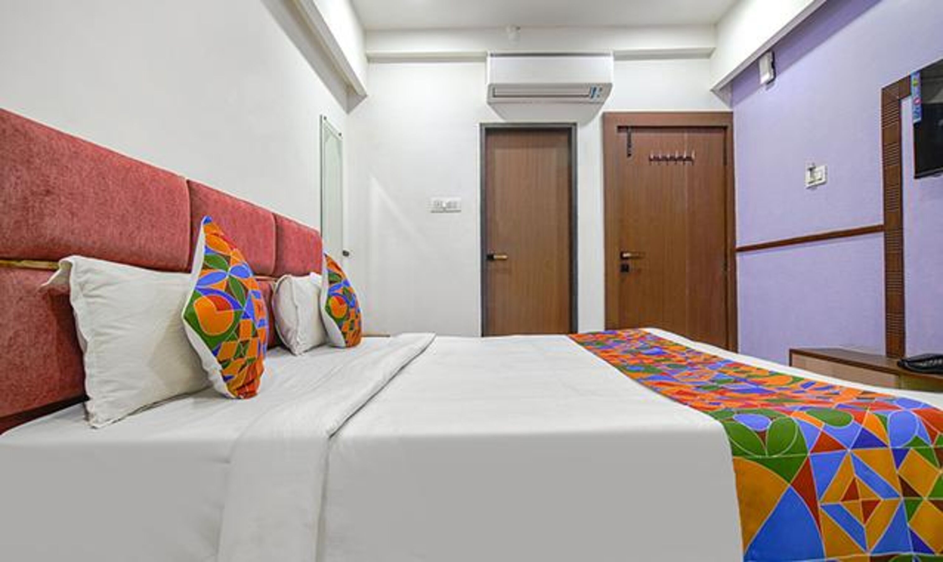 A hotel room with a bed, a desk, and a television.