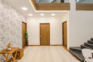 A modern interior with a wooden door, a small table with a plant, and a staircase. - FabHotel Sky Lark Farm (Ludhiana)