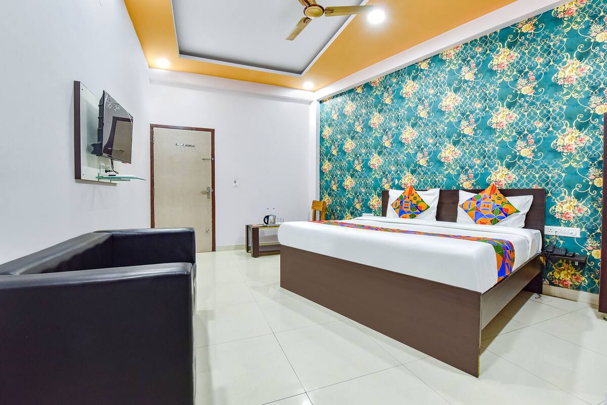A modern hotel room with a large bed, a flat-screen TV mounted on the wall, and a ceiling fan.
