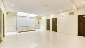 A spacious, well-lit hallway with a tiled floor, a handrail, and two doors. - FabExpress Alacia Inn (Lucknow)