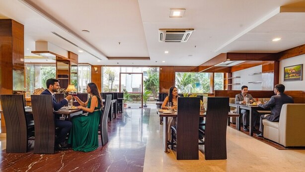 A modern dining area with marble flooring, wooden paneling, and large windows offering a view of greenery. - FabHotel Chris - Whitefield near KTPO & ITPL (Bengaluru)